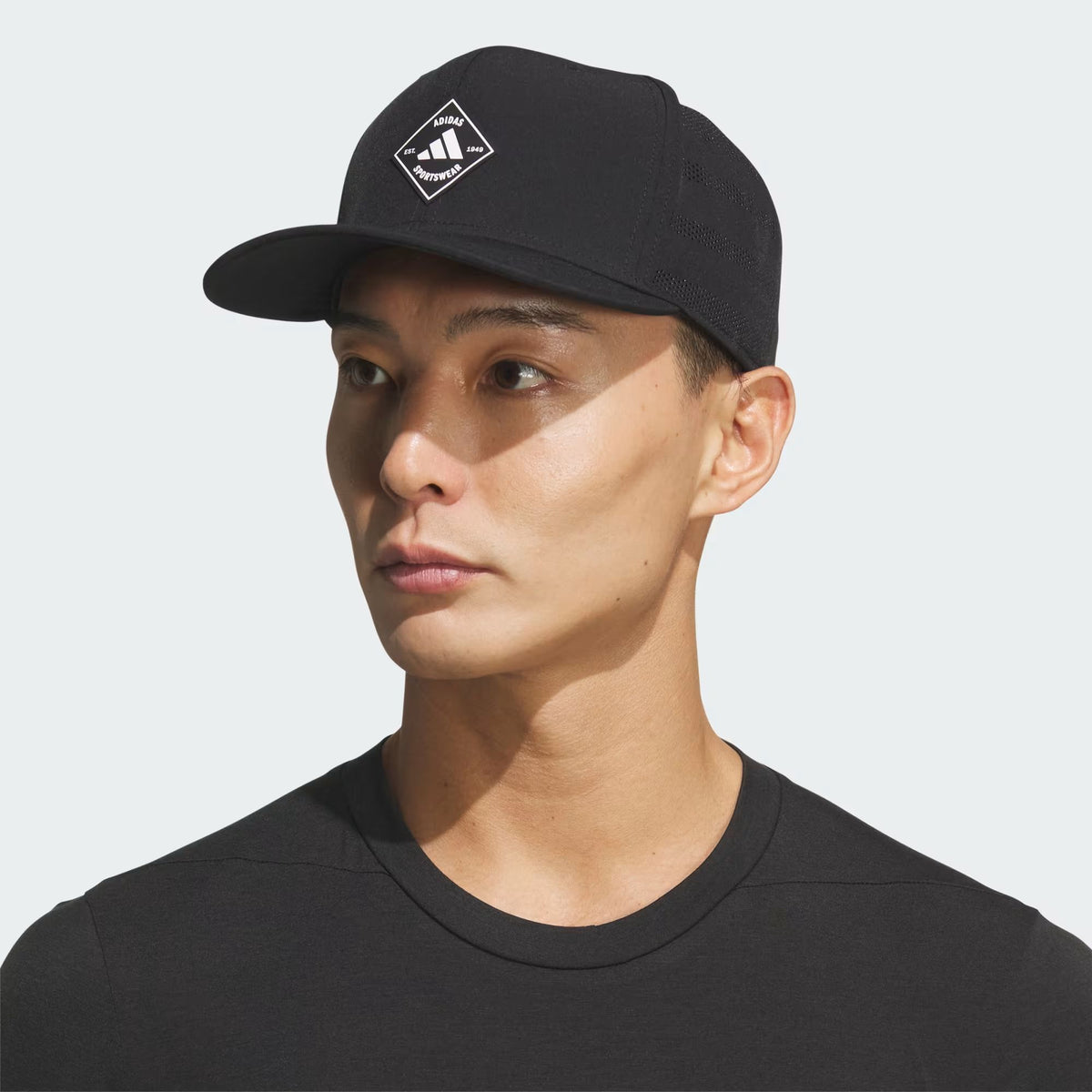 Homme portant la casquette Adidas Quick Dry Snapback noire, vue de trois quarts avec l'écusson losange adidas