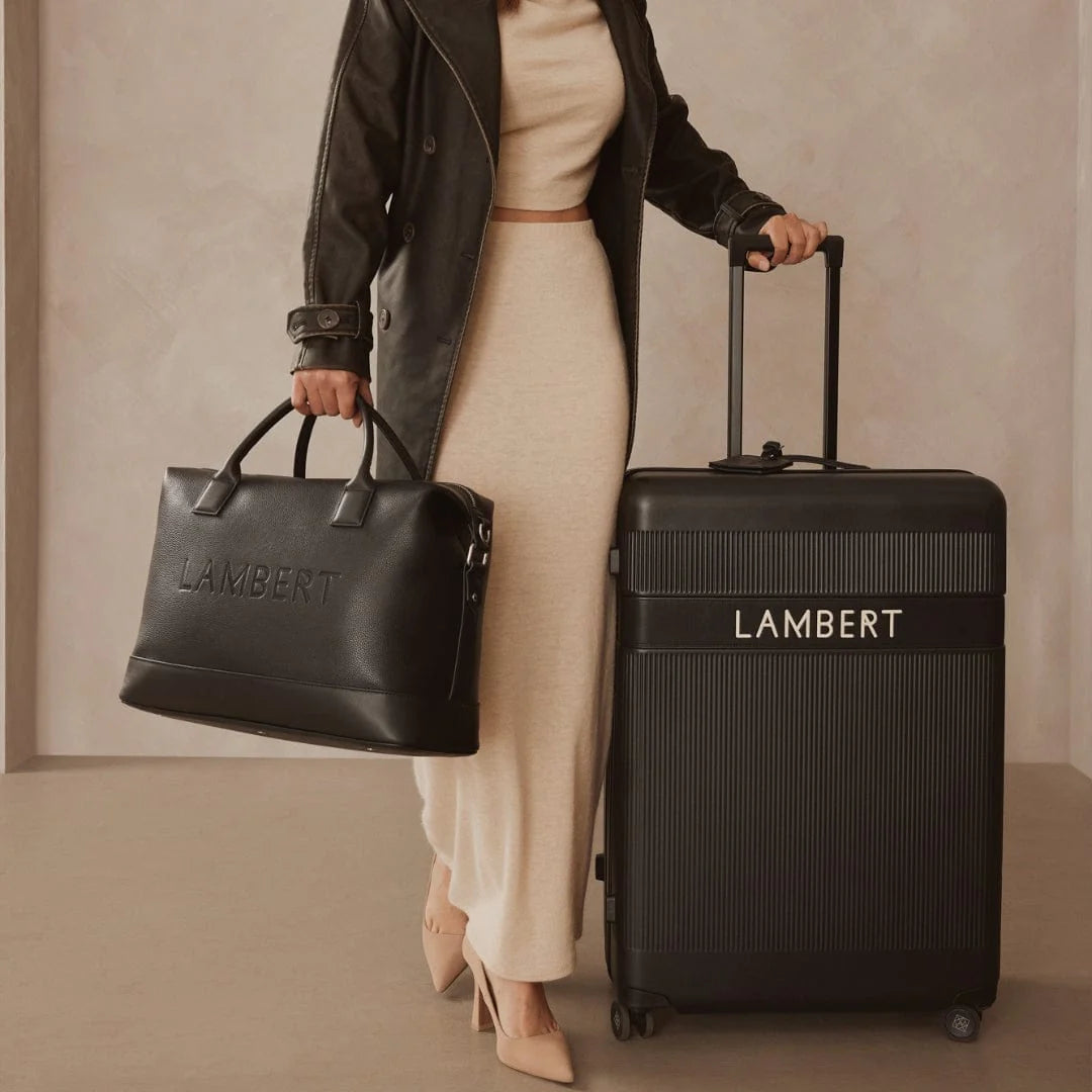 Sac MAE Lambert Design pour femmes, noir, porté près d’une valise