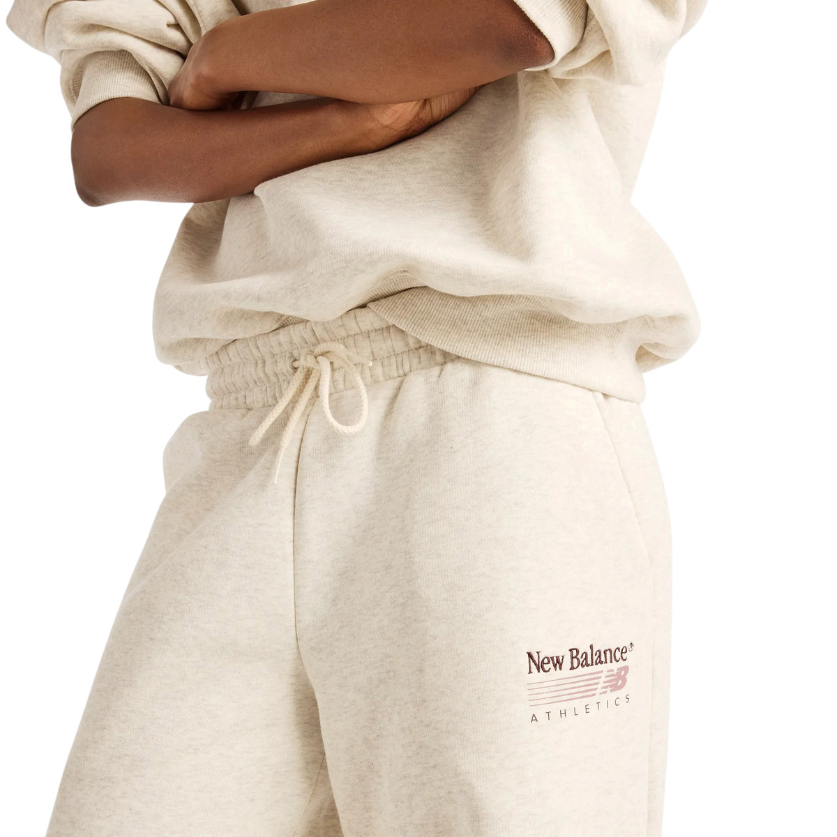 Détail de la taille à cordon et du logo New Balance Athletics du pantalon Trackside beige pour femmes