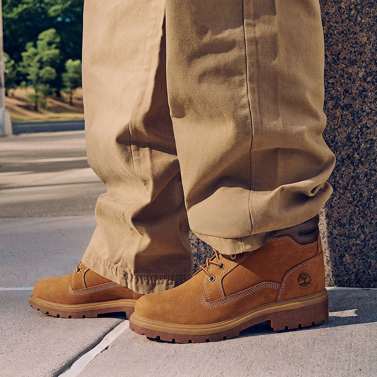 Homme portant la botte Timberland Auburn Falls tan avec un pantalon beige, vue de côté sur un trottoir