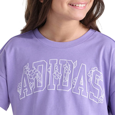 Gros plan du logo Adidas orné de fleurs et de l'encolure ras du cou du T-shirt Adidas lilas pour filles