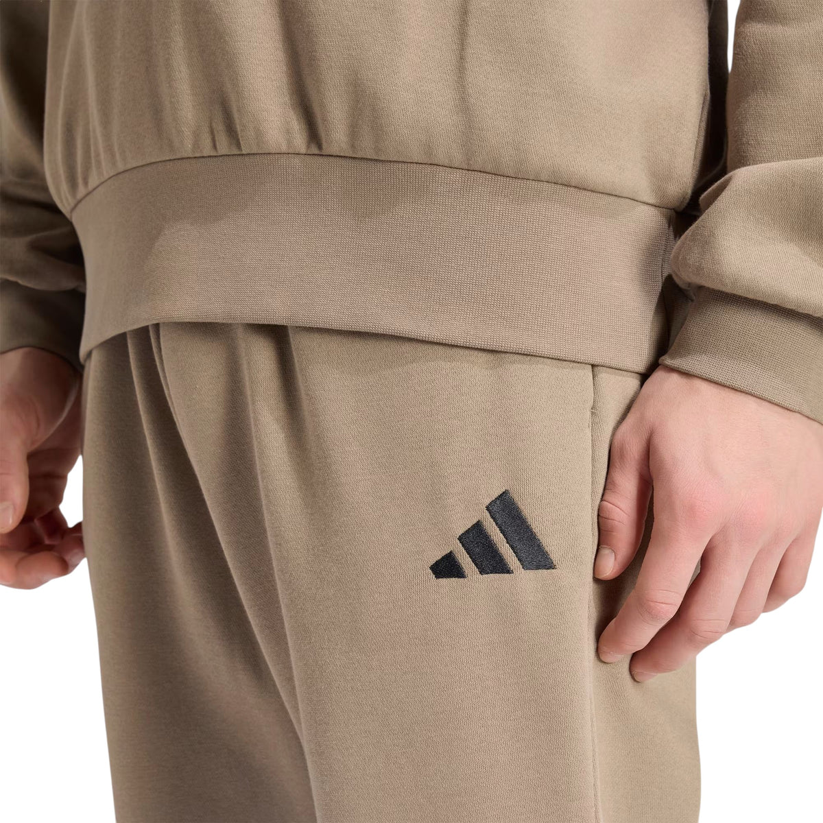 Détail du logo Adidas sur le pantalon Feelcozy Fleece pour hommes, kaki