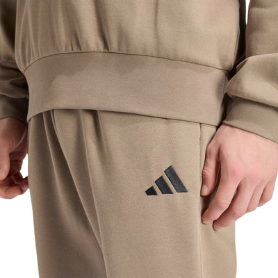 Détail du logo Adidas sur le pantalon Feelcozy Fleece pour hommes, kaki