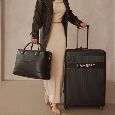 Sac MAE Lambert Design pour femmes, noir, porté près d’une valise