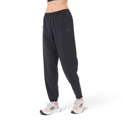 Femme de face portant le pantalon de jogging New Balance RC Essential noir avec des souliers New Balance
