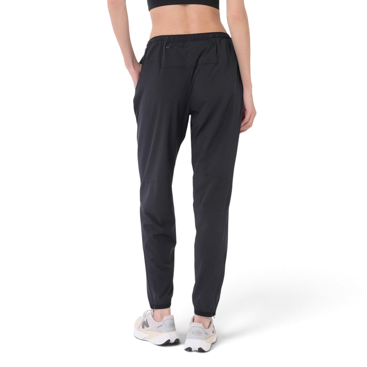 Femme de dos portant le pantalon de jogging New Balance RC Essential noir