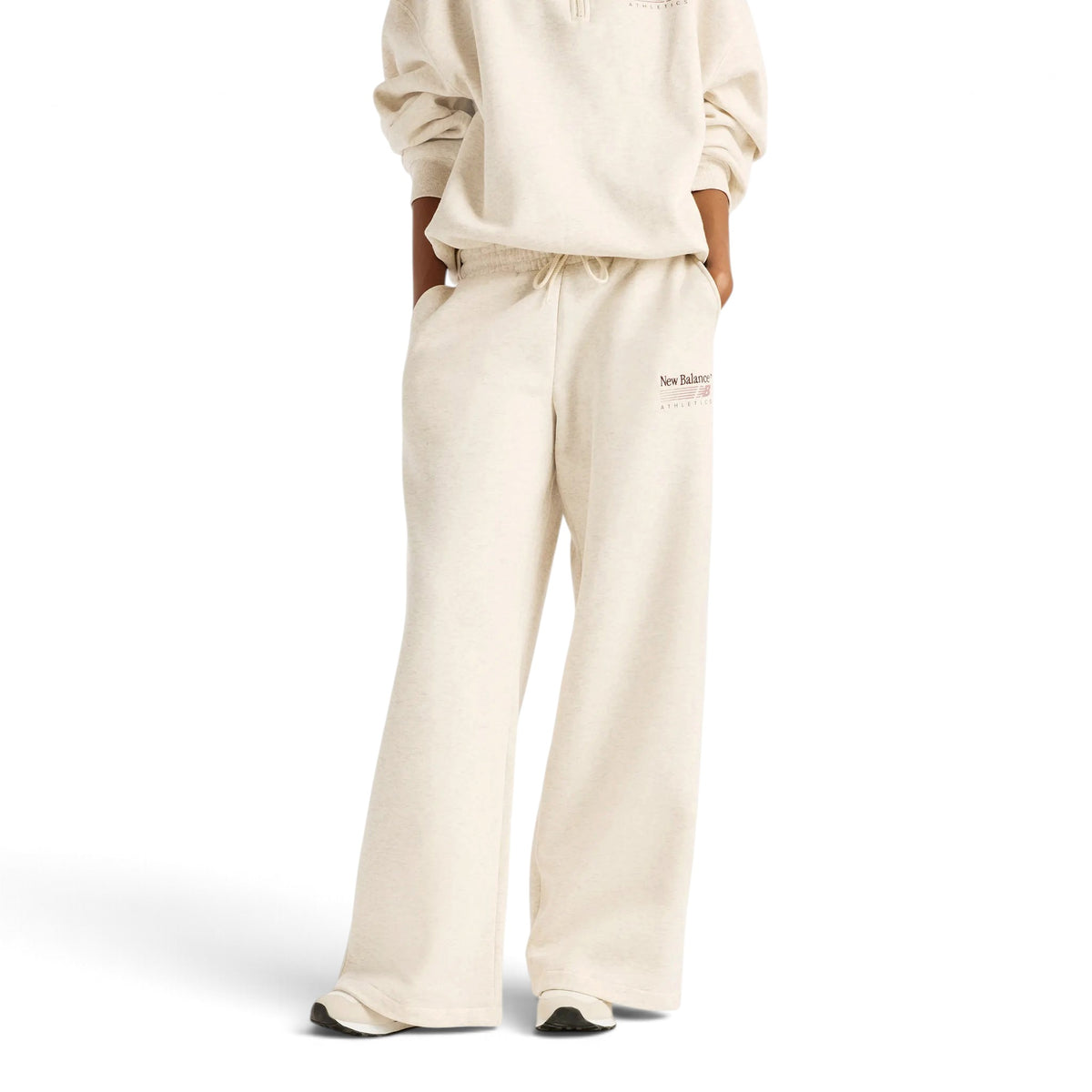 Femme de face portant le pantalon New Balance Trackside beige à jambes larges avec un haut assorti