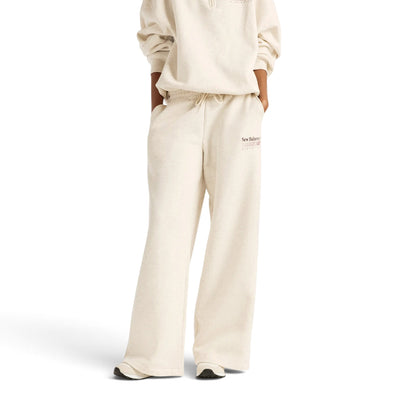 Femme de face portant le pantalon New Balance Trackside beige à jambes larges avec un haut assorti