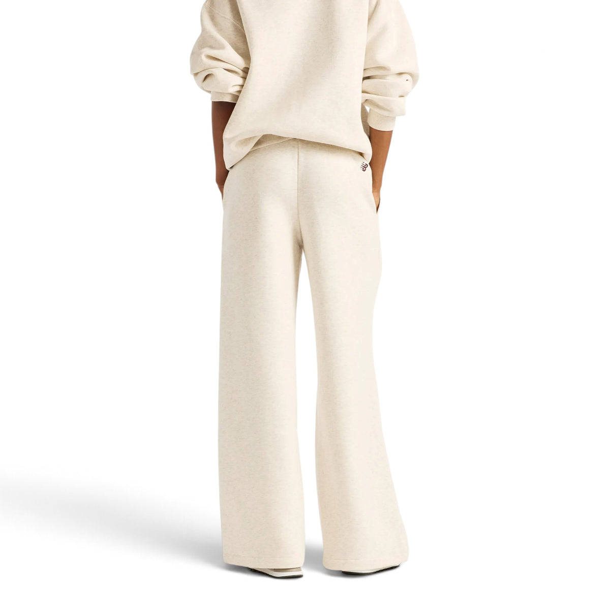 Femme de dos portant le pantalon New Balance Trackside beige à jambes larges