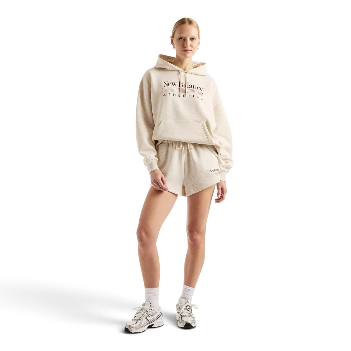 Femme en pied portant le coton ouaté à capuchon New Balance Trackside beige avec un short assorti