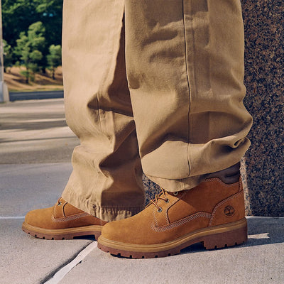 Homme portant la botte Timberland Auburn Falls tan avec un pantalon beige, vue de côté sur un trottoir